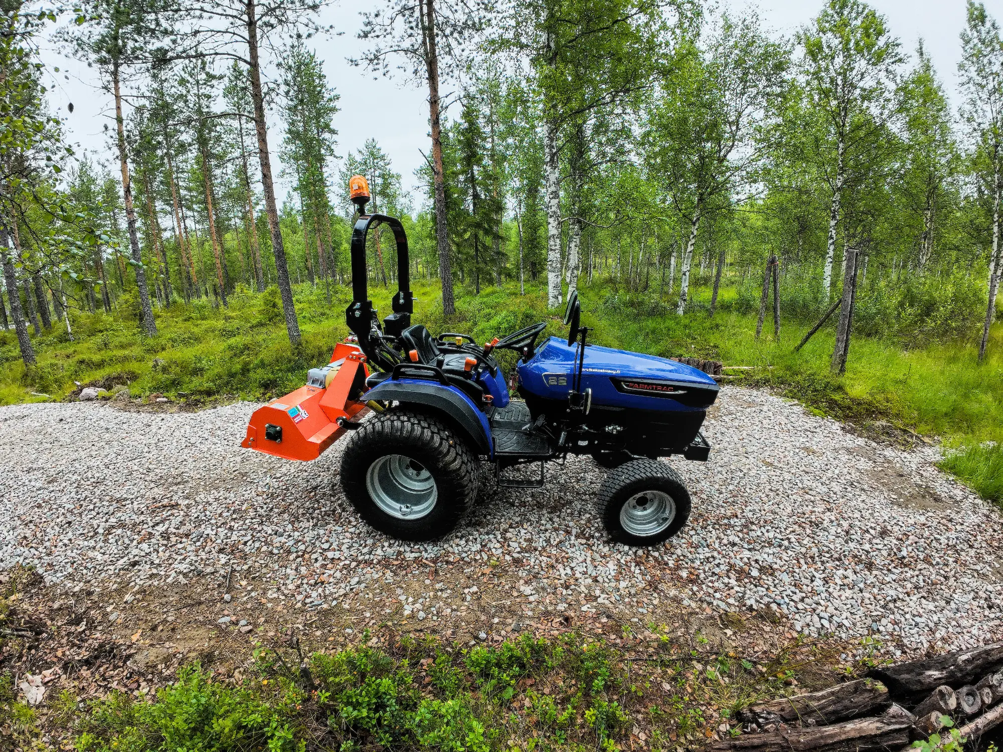 Tilan ensimmäinen traktori ja riviväliniittokone metsän laidassa